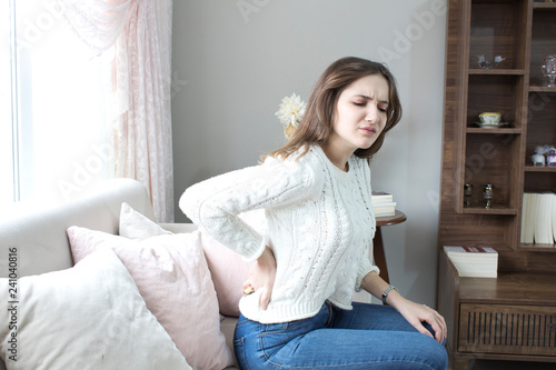 Beautiful young woman suffering from backache at home 