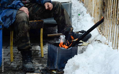 a man is burning a fire to warm up in a winter day