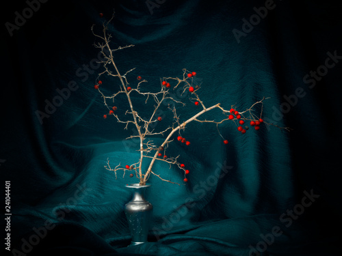 Winter red berries in a vase with turquoise fabric, light painting still life. Decorative. photo