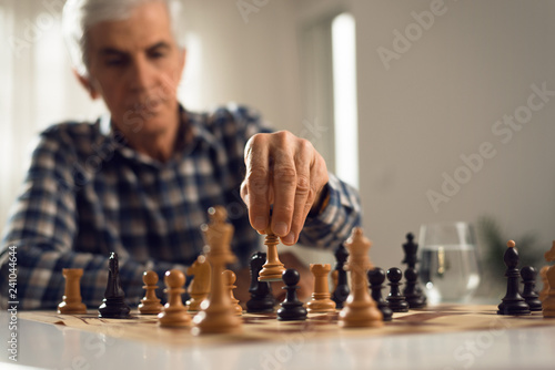 Close up of senior man playing chess at home