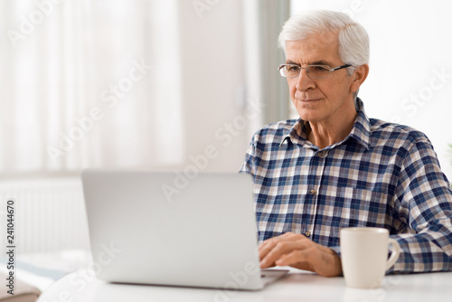 Happy mature man relaxing at home and using laptop