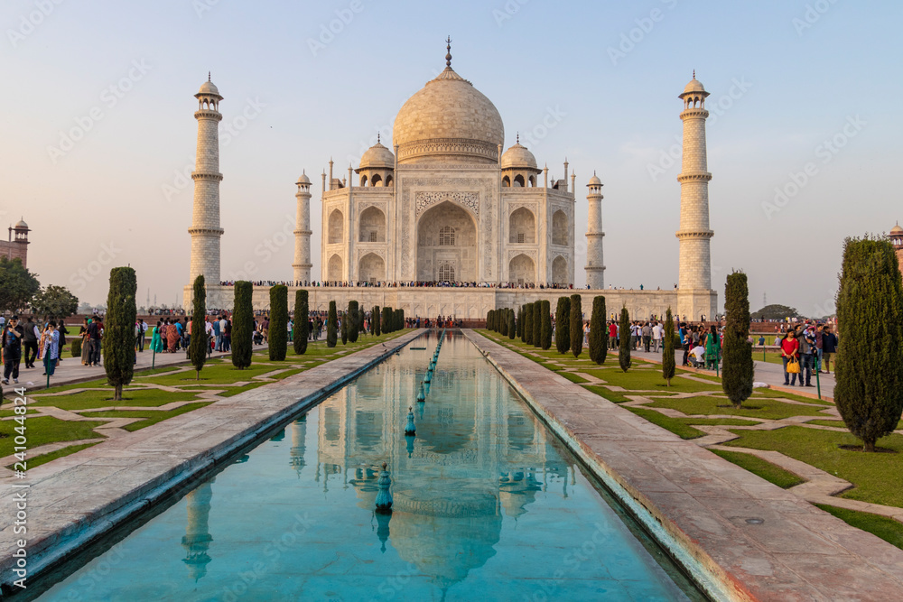 Fototapeta premium Taj Mahal Agra with Mughal architecture gateway at sunset with water reflection.