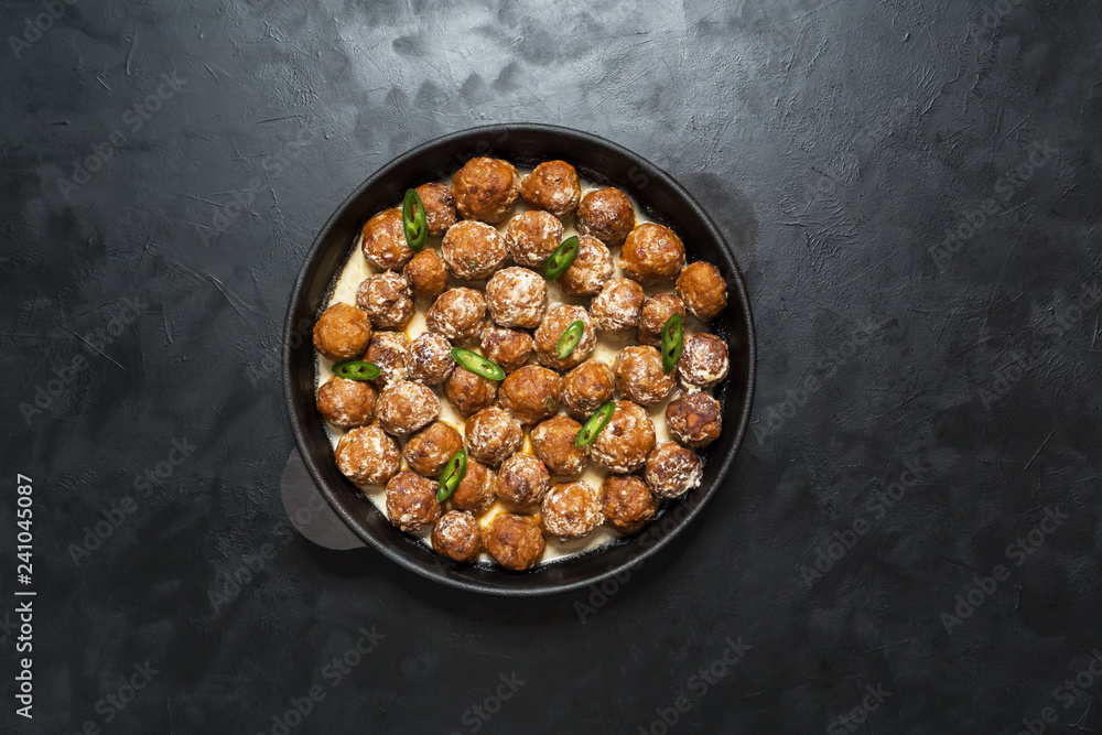 Juicy diet meatballs in a frying pan on a black table.