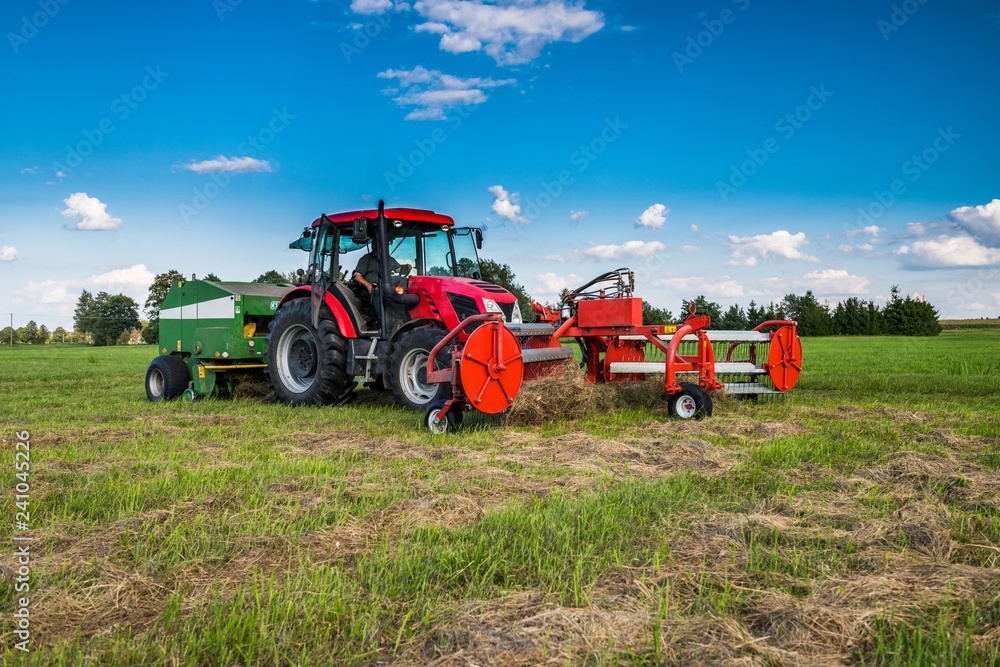 Obraz premium Nowoczesny traktor podczas zbioru siana. Baloty. Lato