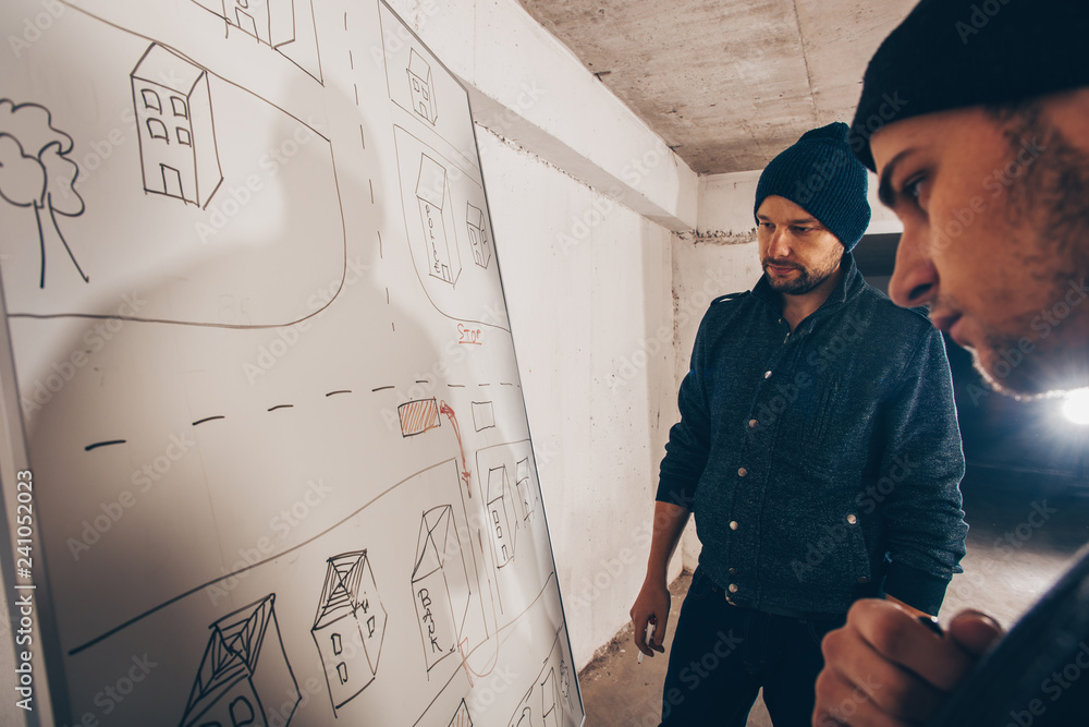Thiefs prepare for heist while making plan on a map Thiefs prepare for heist while making plan on a map