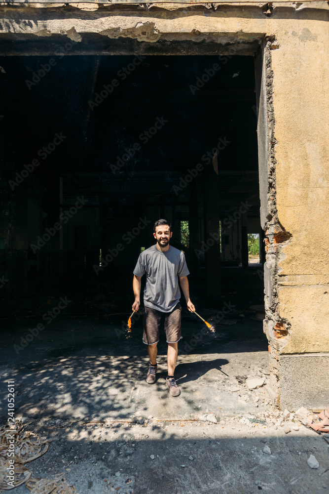 Young man in abandoned factory holding firework candle