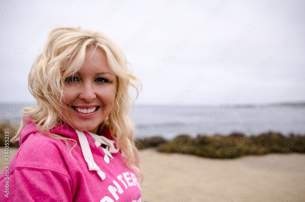 Beautiful blonde woman with beach waves and touseled hair stands and poses on a windy beach along the Pacific Coast Highway in California Beautiful blonde woman with beach waves and touseled hair stands and poses on a windy beach along the Pacific Coast Highway in California
