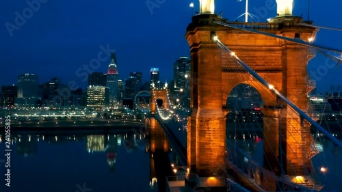 Tracking shot of Cincinnati skyline over Roebling bridge in the evening with lights