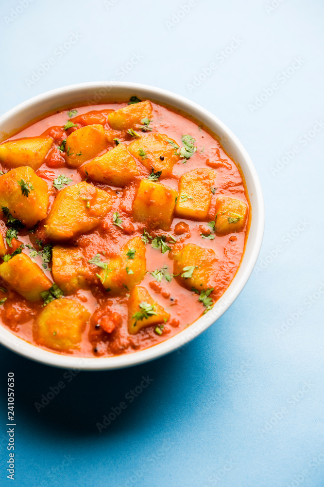 Indian food - Aloo curry masala. Potato cooked with spices and herbs in a tomato curry. served in a bowl over moody background. selective focus Indian food - Aloo curry masala. Potato cooked with spices and herbs in a tomato curry. served in a bowl over moody background. selective focus