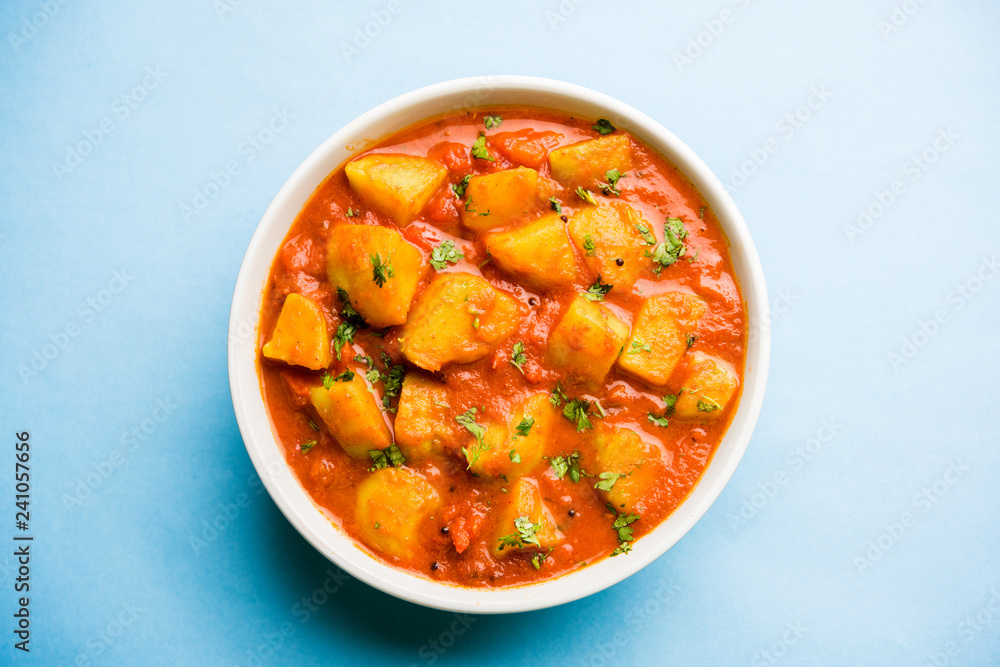 Indian food - Aloo curry masala. Potato cooked with spices and herbs in a tomato curry. served in a bowl over moody background. selective focus Indian food - Aloo curry masala. Potato cooked with spices and herbs in a tomato curry. served in a bowl over moody background. selective focus