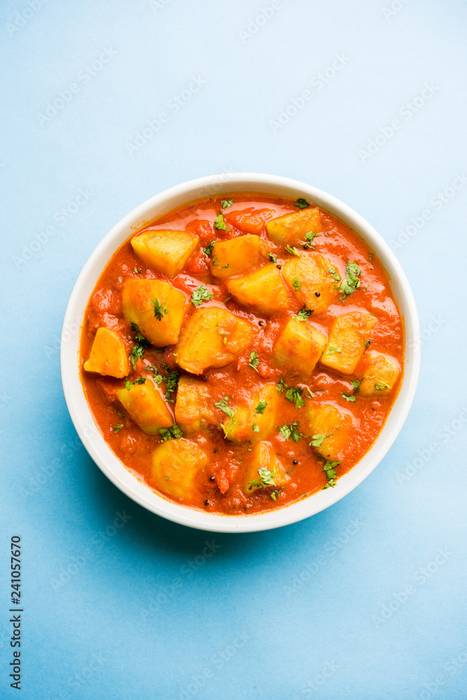 Indian food - Aloo curry masala. Potato cooked with spices and herbs in a tomato curry. served in a bowl over moody background. selective focus Indian food - Aloo curry masala. Potato cooked with spices and herbs in a tomato curry. served in a bowl over moody background. selective focus