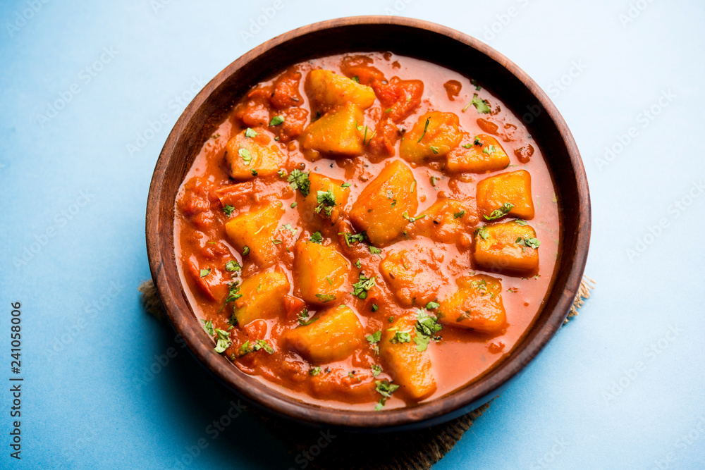 Indian food - Aloo curry masala. Potato cooked with spices and herbs in a tomato curry. served in a bowl over moody background. selective focus Indian food - Aloo curry masala. Potato cooked with spices and herbs in a tomato curry. served in a bowl over moody background. selective focus