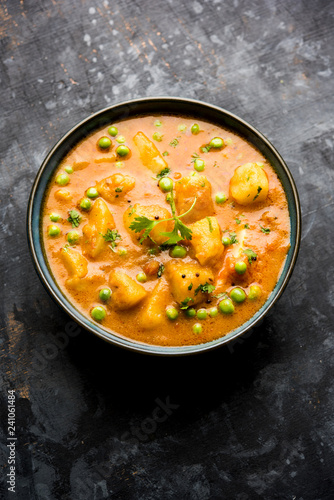 Indian Aloo Mutter curry - Potato and Peas immersed in an Onion Tomato Gravy and garnished with coriander leaves. Served in a Karahi/kadhai or pan or bowl. selective focus