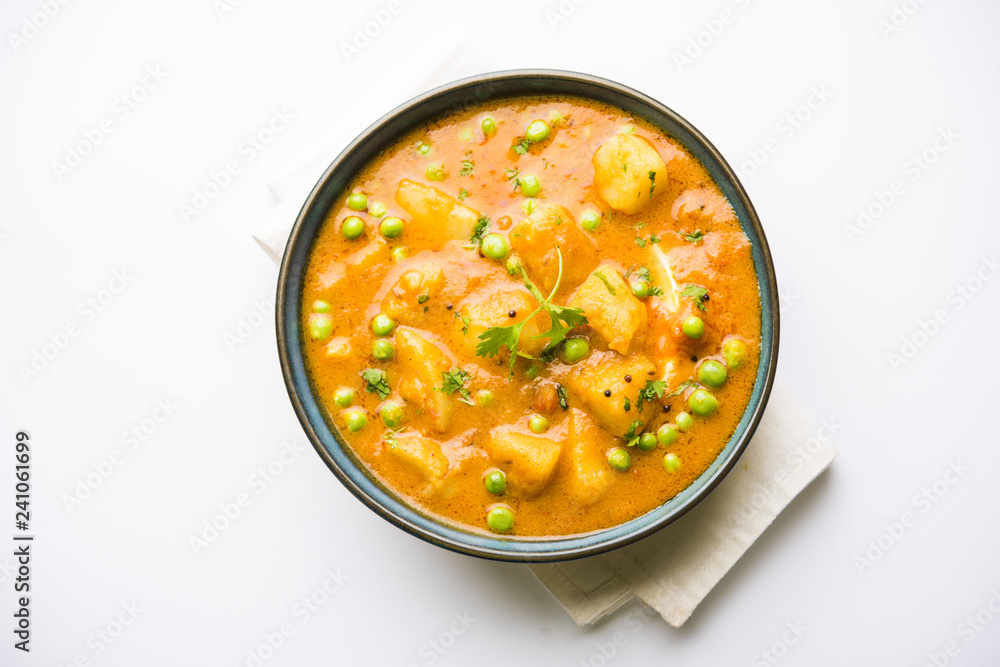 Indian Aloo Mutter curry - Potato and Peas immersed in an Onion Tomato Gravy and garnished with coriander leaves. Served in a Karahi/kadhai or pan or bowl. selective focus Indian Aloo Mutter curry - Potato and Peas immersed in an Onion Tomato Gravy and garnished with coriander leaves. Served in a Karahi/kadhai or pan or bowl. selective focus