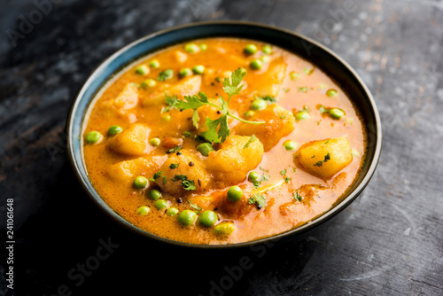 Indian Aloo Mutter curry - Potato and Peas immersed in an Onion Tomato Gravy and garnished with coriander leaves. Served in a Karahi/kadhai or pan or bowl. selective focus