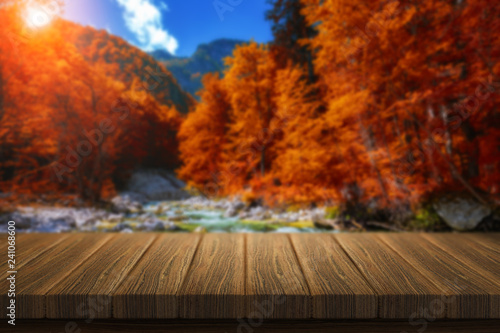 Empty wooden table for product placement or montage with focus to table top in the foreground. Mock up for display of product. Beautiful background with forest  waterfall  incredible landscape.