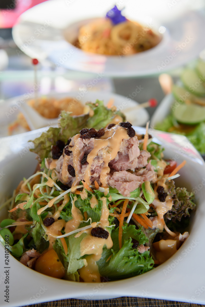 Tuna salad placed in a white circular ceramic dish topped with salad dressing and garnished with dried baby raisins Tuna salad placed in a white circular ceramic dish topped with salad dressing and garnished with dried baby raisins