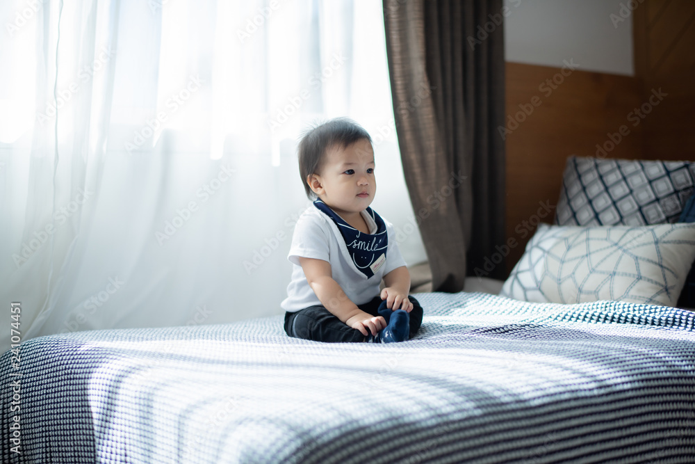 The baby smiled happily sitting in the bed in the bedroom. The baby smiled happily sitting in the bed in the bedroom.