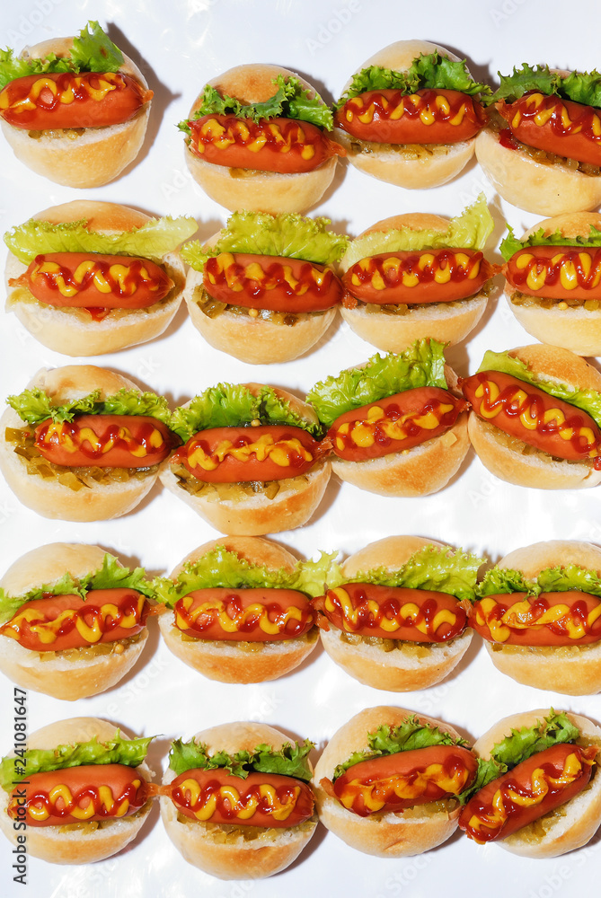 Mini hot dog bread with mustard and ketchup on party table Mini hot dog bread with mustard and ketchup on party table