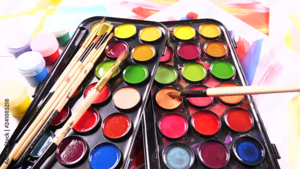 Paint brushes and watercolor paints in motion on the table Paint brushes and watercolor paints in motion on the table