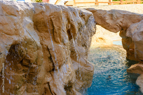 Small waterfall with turquoise water in the hotel pool