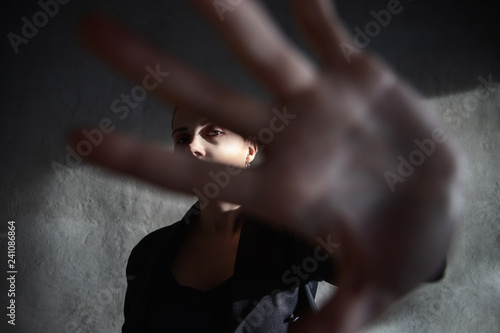 Girl with short haircut hides her face with hand