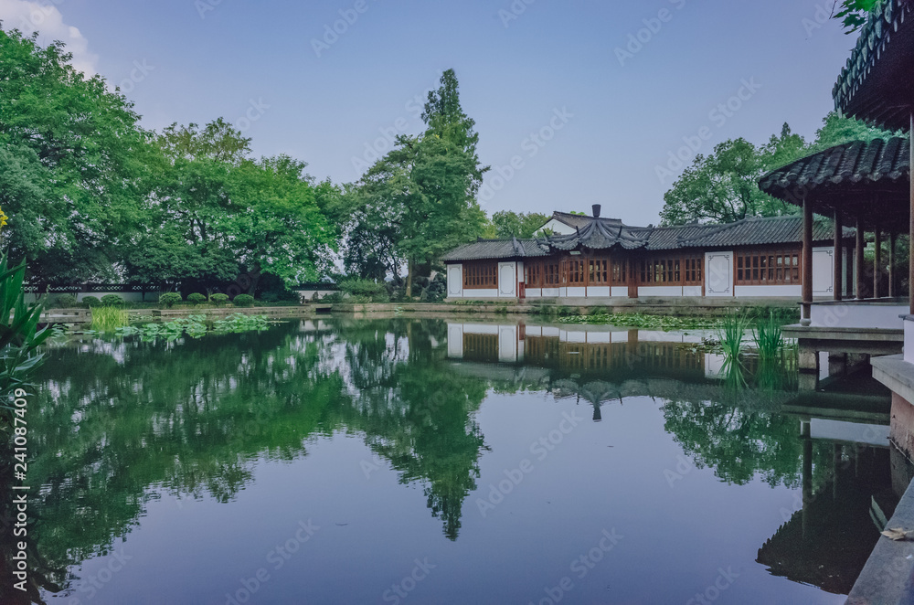 Traditional Chinese house by pond with reflection in water, in a Chinese garden, near West Lake, Hangzhou, China
