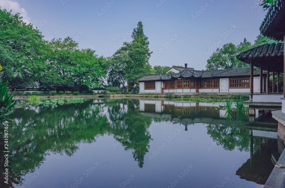 Traditional Chinese house by pond with reflection in water, in a Chinese garden, near West Lake, Hangzhou, China Traditional Chinese house by pond with reflection in water, in a Chinese garden, near West Lake, Hangzhou, China