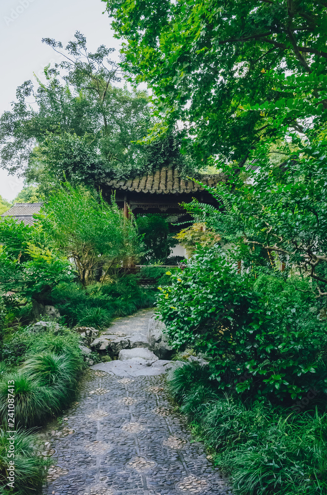 Path leading too a traditional Chinese pavilion among trees, in a Chinese garden, near West Lake, Hangzhou, China