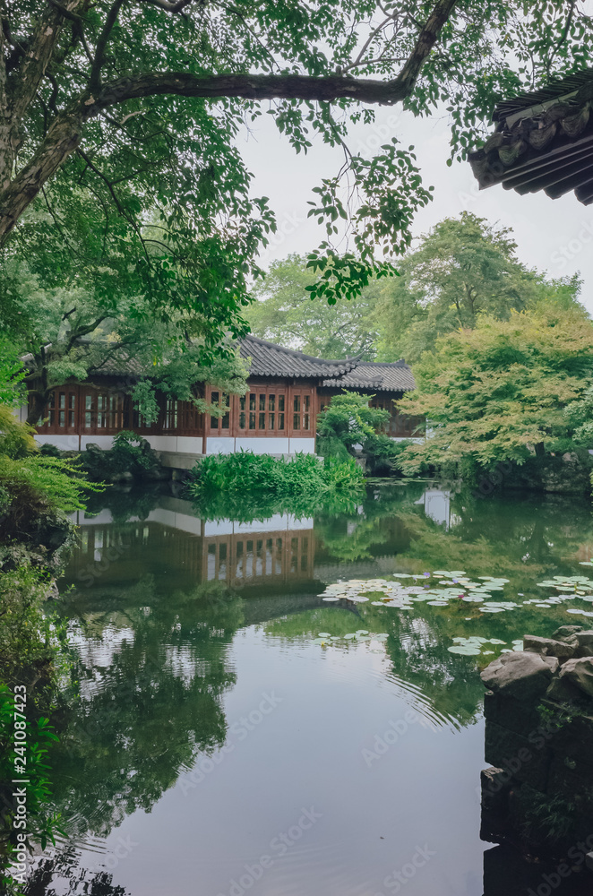 Traditional Chinese house by pond with reflection in water, in a Chinese garden, near West Lake, Hangzhou, China Traditional Chinese house by pond with reflection in water, in a Chinese garden, near West Lake, Hangzhou, China