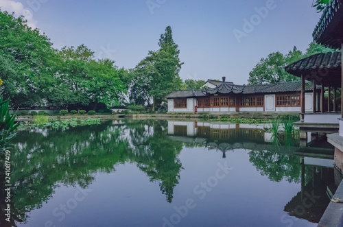 Traditional Chinese house by pond with reflection in water, in a Chinese garden, near West Lake, Hangzhou, China