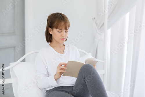 Free Download Beautiful Attractive Asian woman sitting on bed in bedroom reading book for learn and education smile and positive thinking feeling so happiness and comfortable,Education Concept - GFXLoad