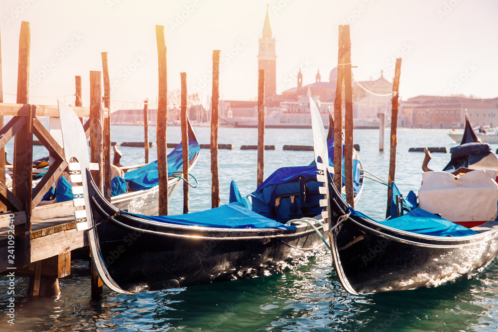 Three blue gondolas moored at pier in city on water Venice, European cityscape background.