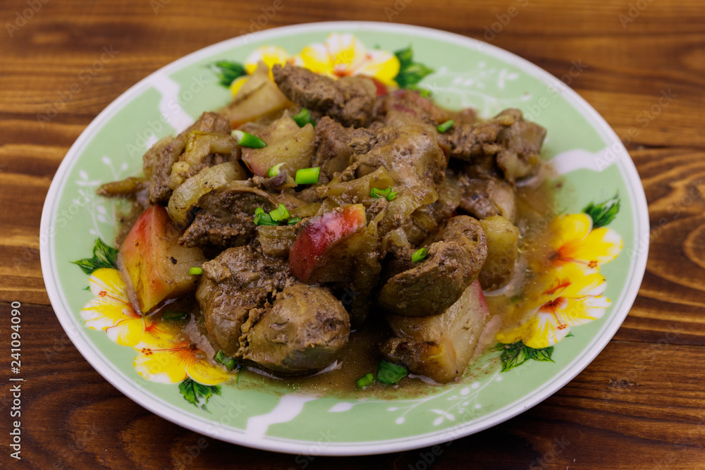 Stewed chicken liver with apple and onion on wooden table Stewed chicken liver with apple and onion on wooden table