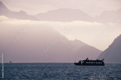 Boat on Swiss alke Luzern with mountain cliffs background silhouette view