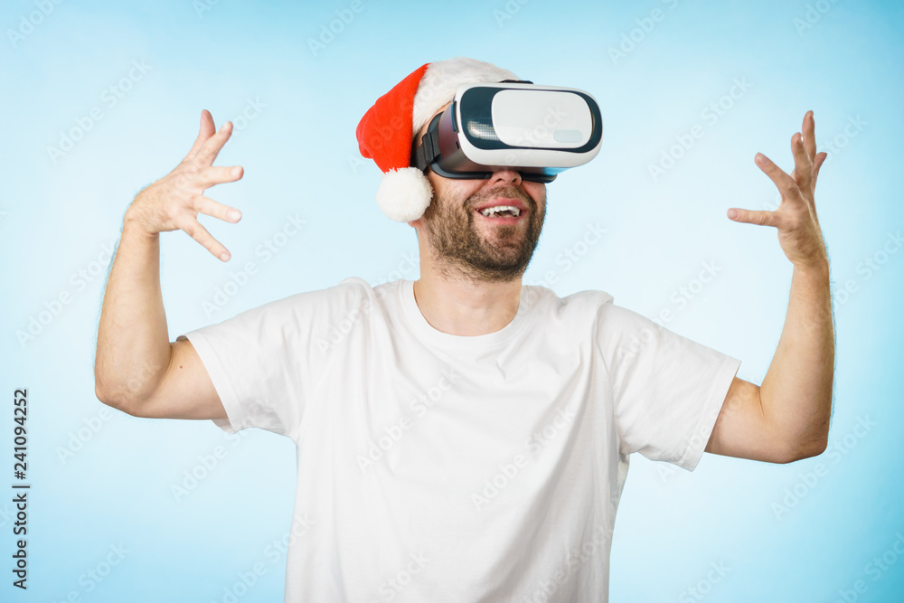 Naklejka premium Man in virtual reality goggles and santa hat