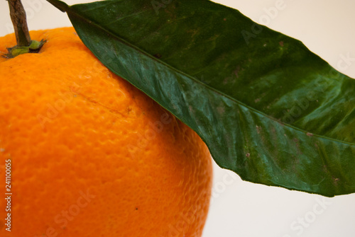 Close up of a single fresh orange with green leaf
