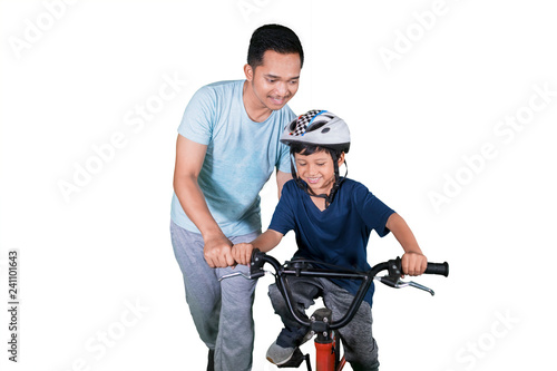 Happy child learns to ride a bike with his father
