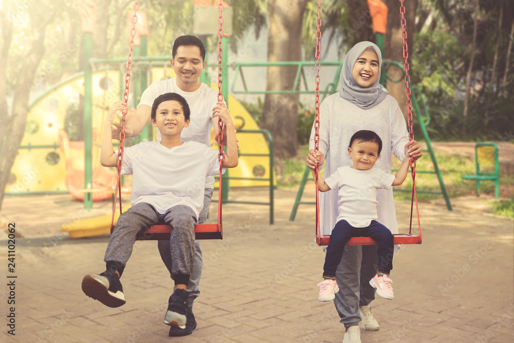 Happy Parents Pushing Their Children On A Swing Stock Photo Adobe Stock