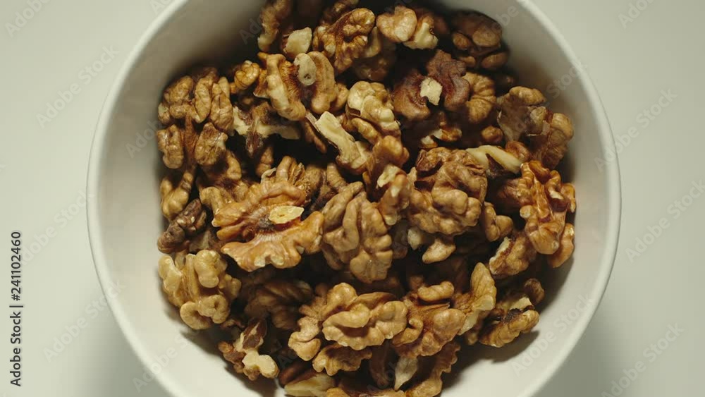 SLOW MOTION: Walnuts falling into a white bowl - Top View SLOW MOTION: Walnuts falling into a white bowl - Top View
