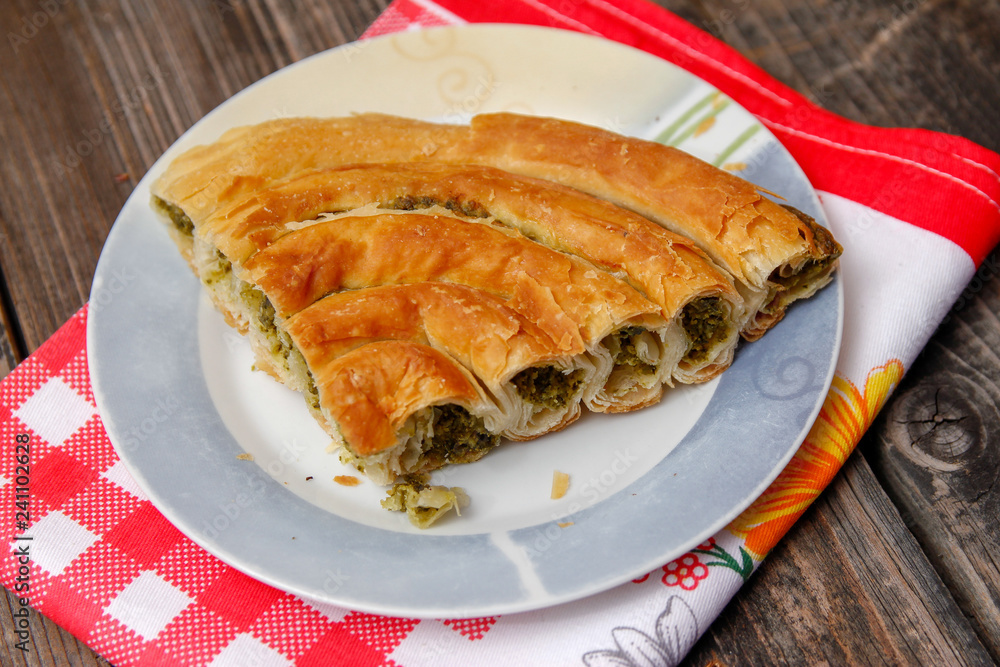 Pastry with cheese and spinach and red dish towel on an retro style wooden table Pastry with cheese and spinach and red dish towel on an retro style wooden table