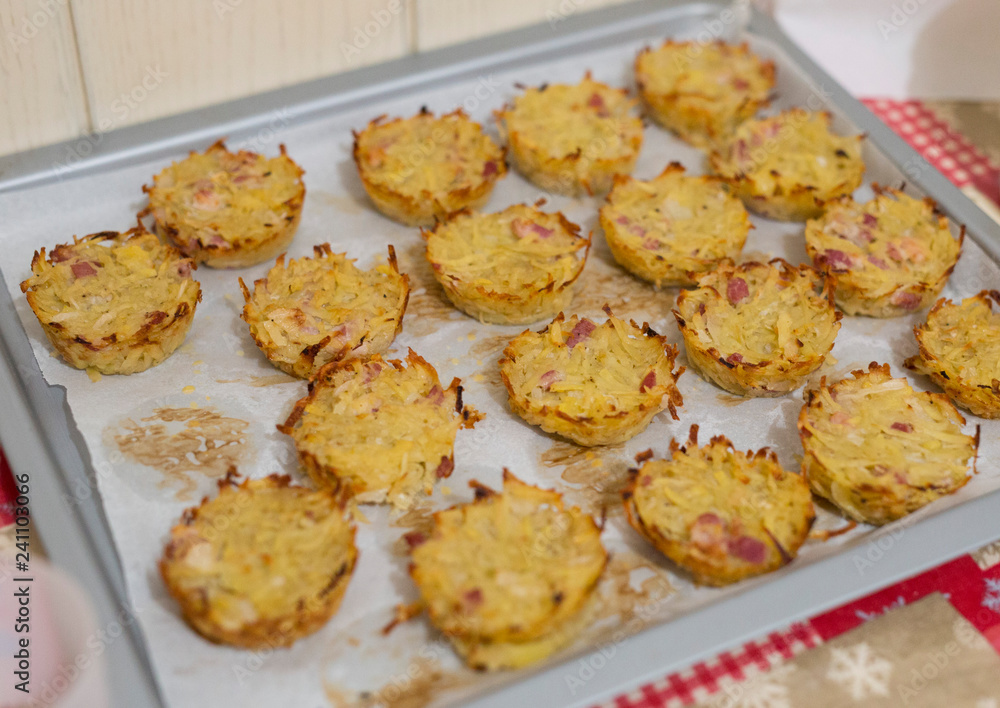 horizontal image with detail of baked pies with potatoes and speck photographed in a pan, prepared for a party