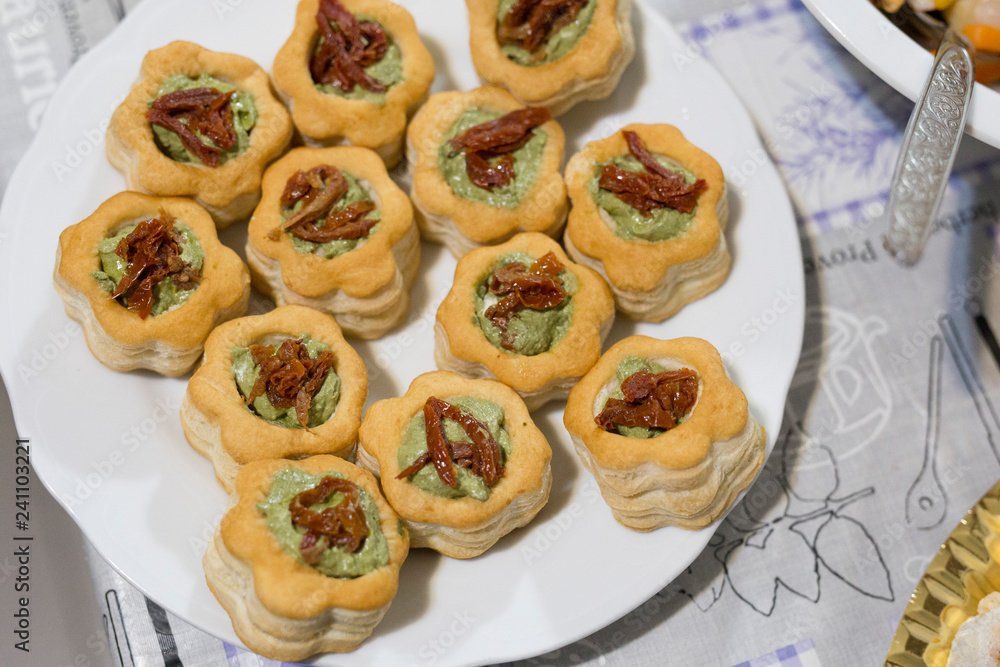horizontal image with vol-au-vent detail with pesto sauce and dried tomatoes, served on a tray and prepared for a party horizontal image with vol-au-vent detail with pesto sauce and dried tomatoes, served on a tray and prepared for a party