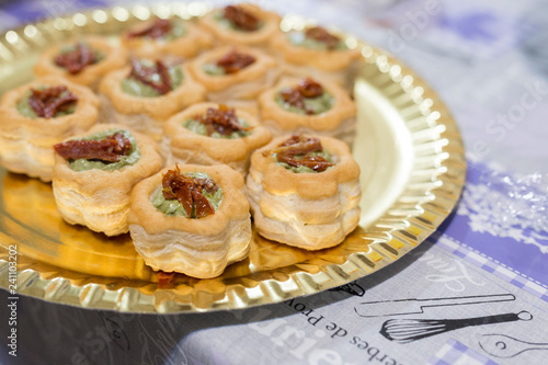 horizontal image with vol-au-vent detail with pesto sauce and dried tomatoes, served on a tray and prepared for a party