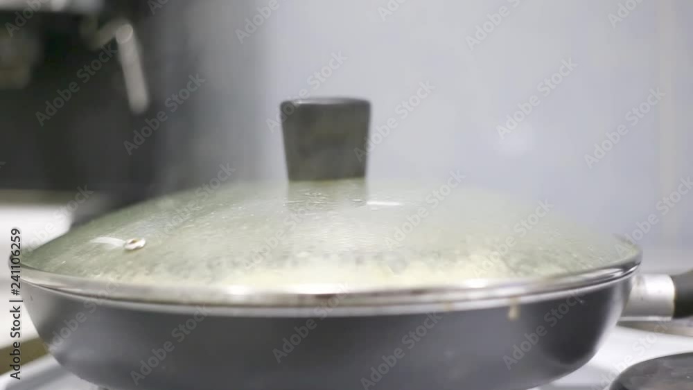 Hot pan stands on the stove. Cooking, simmer in a pan with the lid closed. Hot pan stands on the stove. Cooking, simmer in a pan with the lid closed.