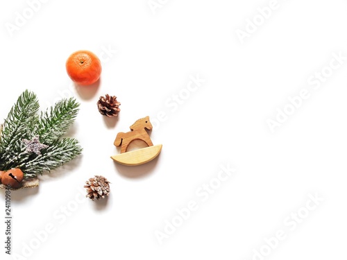 Beautiful New Year mockup in minimalist style for greeting card and banner. Fir tree branch, pine cones, mandarin and wooden horse. Copy space