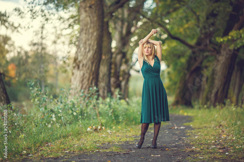 a blonde girl in a green long dress is spinning around an oak grove © hiv360