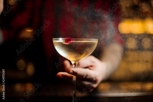 Barman holding elegant cocktail glass with alcoholic drink