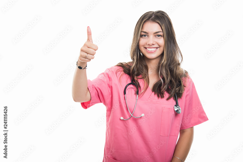 Portrait of beautiful young doctor wearing scrubs showing thumb up Portrait of beautiful young doctor wearing scrubs showing thumb up