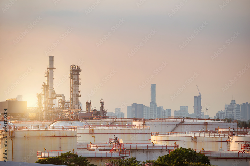 Oil refinery with tank farm in the city during sunset warm tone industry manufacturing gasoline products.